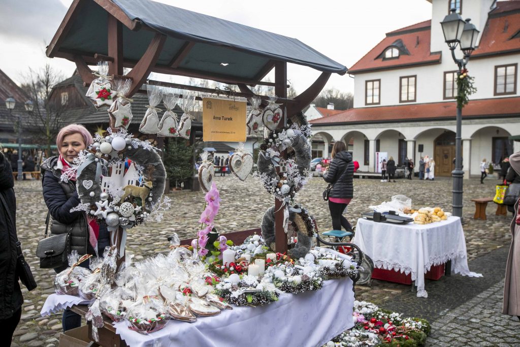 Stoi mały stragan ze świątecznymi stroikami do sprzedaży podczas Bożonarodzeniowego Jarmarku w Miasteczku Galicyjskim. 