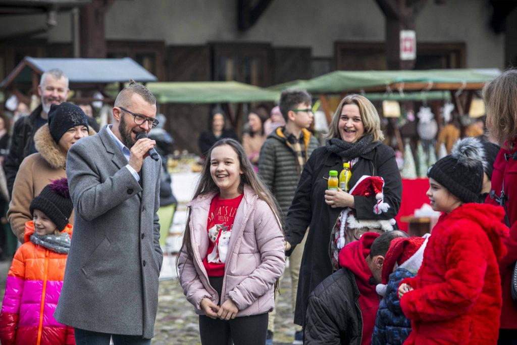 Na rynku Miasteczka Galicyjskiego prowadzący imprezę rozmawia z osobami, które przyszły na Bożonarodzeniowy Jarmark. 