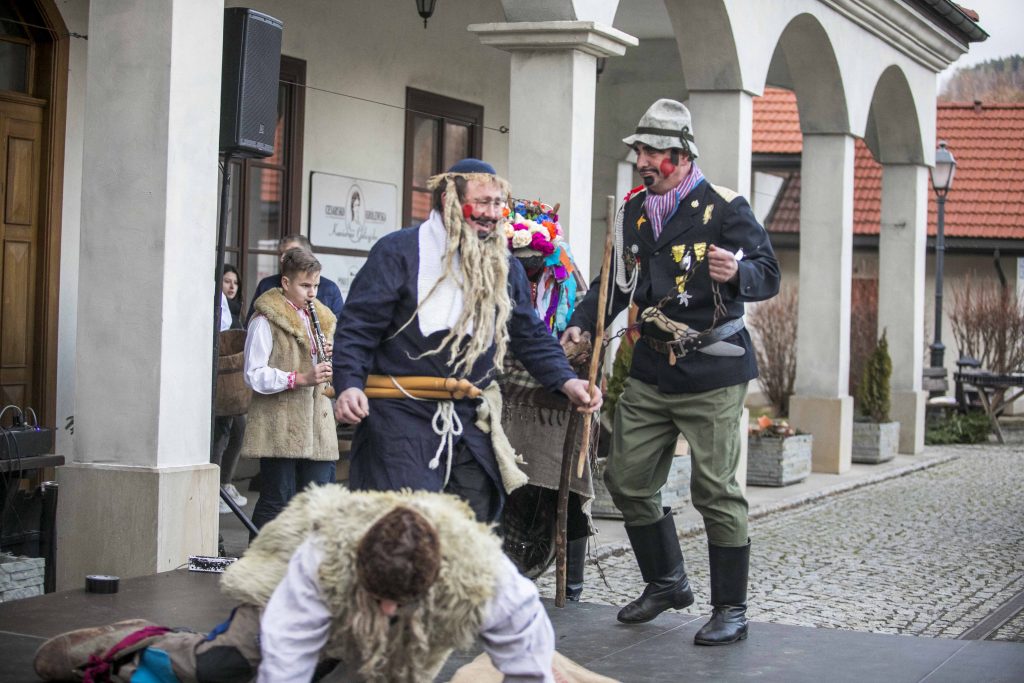 Scena pod ratuszem Miasteczka Galicyjskiego. Na scenie aktorzy przebrani w stroje ludowe odgrywają śmieszną świąteczną scenkę. Trwa Bożonarodzeniowy Jarmark. 