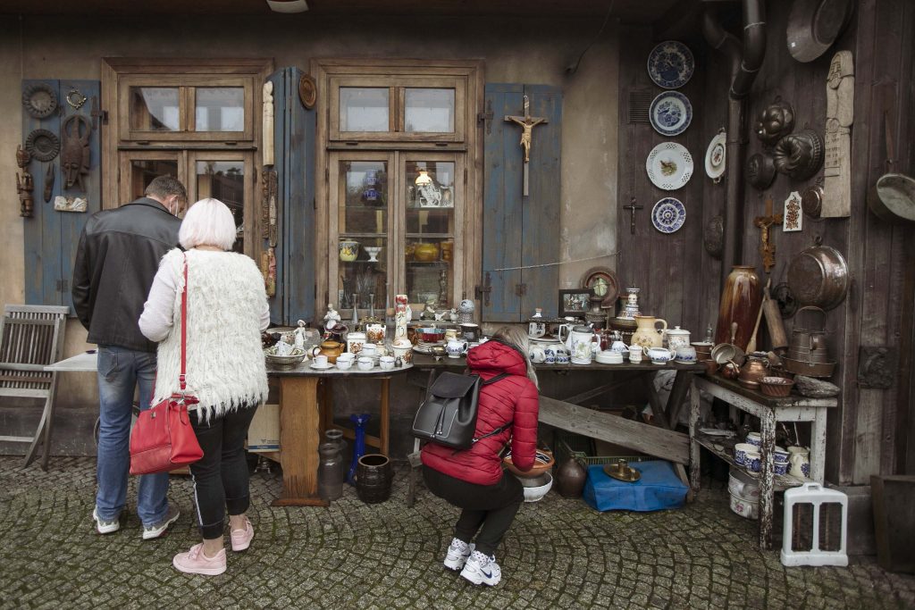 Dwie kobiety i mężczyzna oglądają wystawę antyków w budynku antykwariatu w Miasteczku Galicyjskim podczas Kiermaszu Staroci.